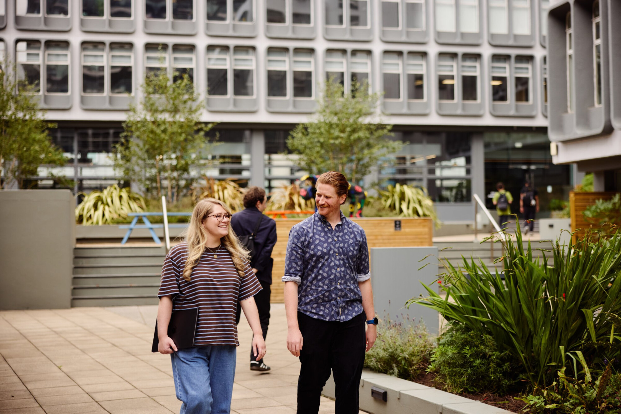 People walking through the planted courtyard at Riverside, Salford.